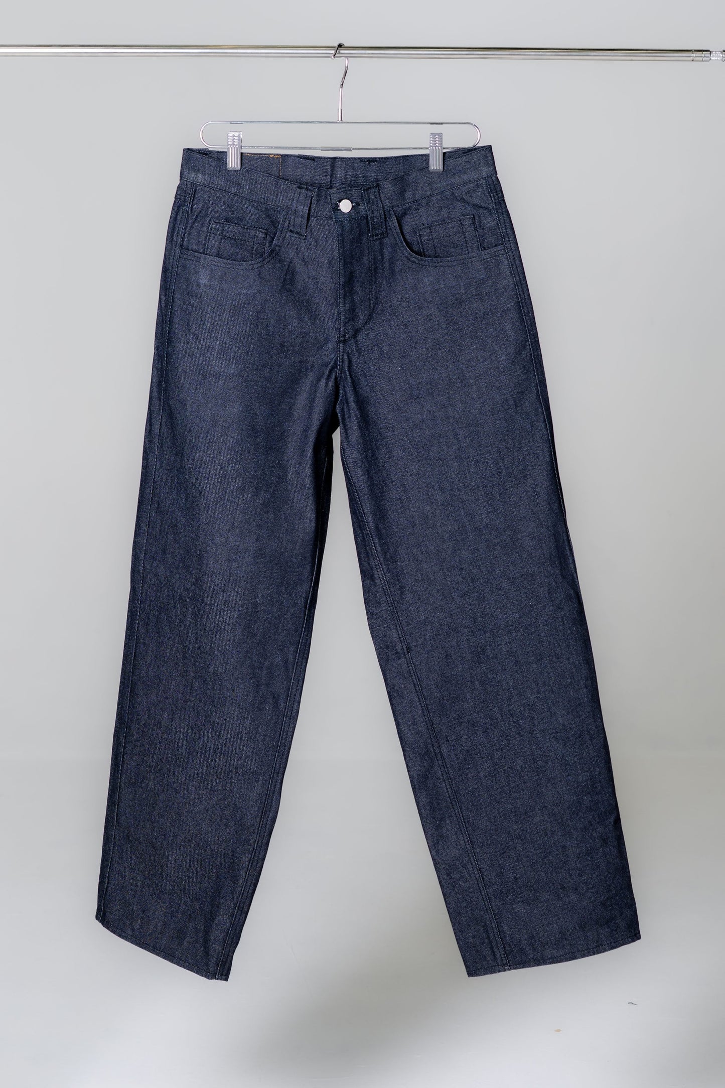 Blue jeans hanging on a rack against a white background
