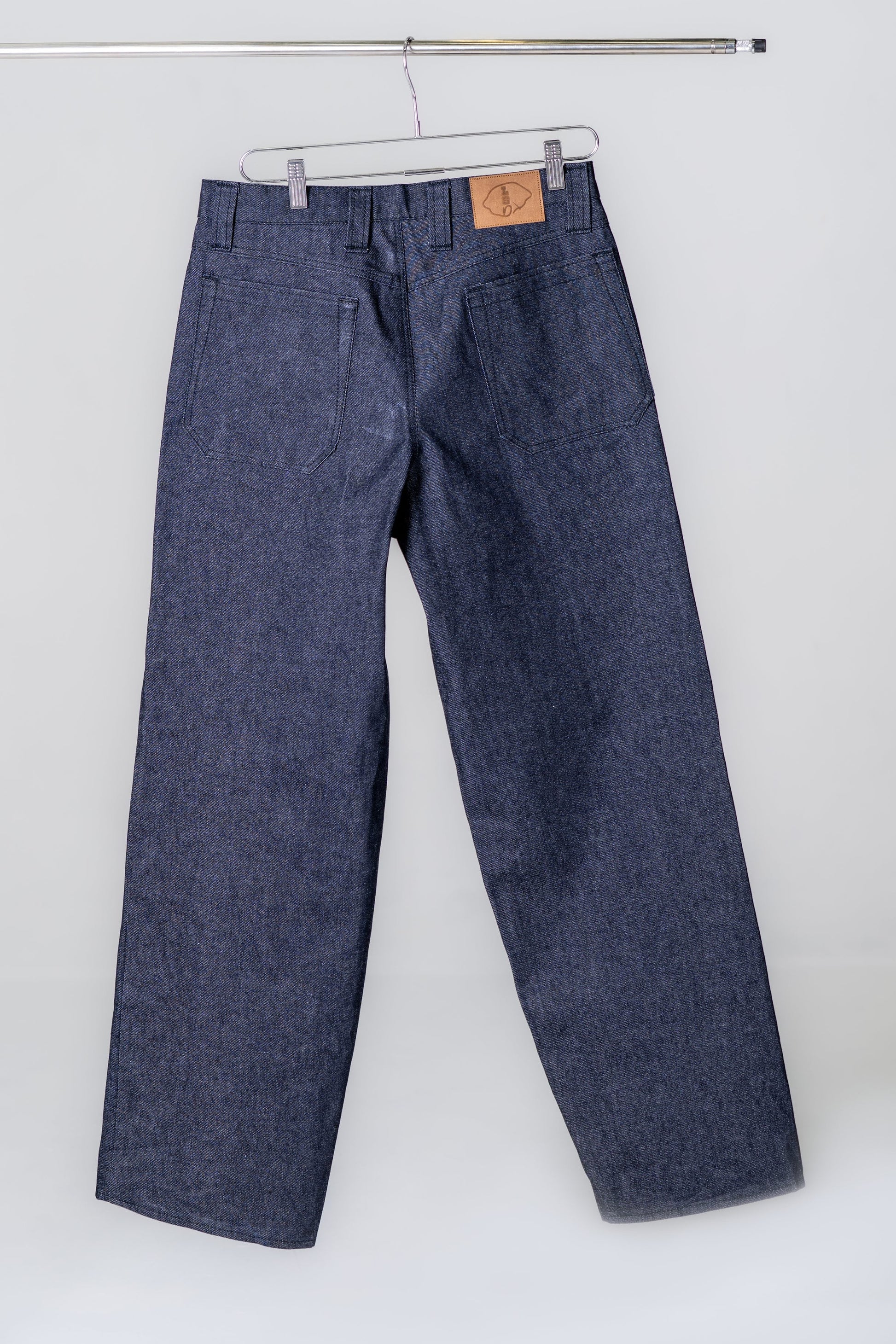 Blue denim pants hanging on a white background