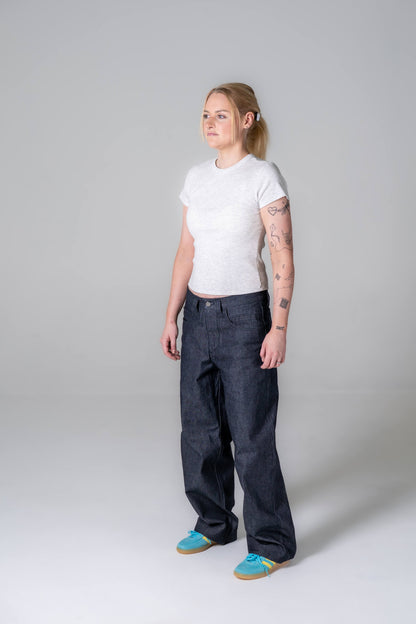Person wearing a white t-shirt and dark pants on a plain background