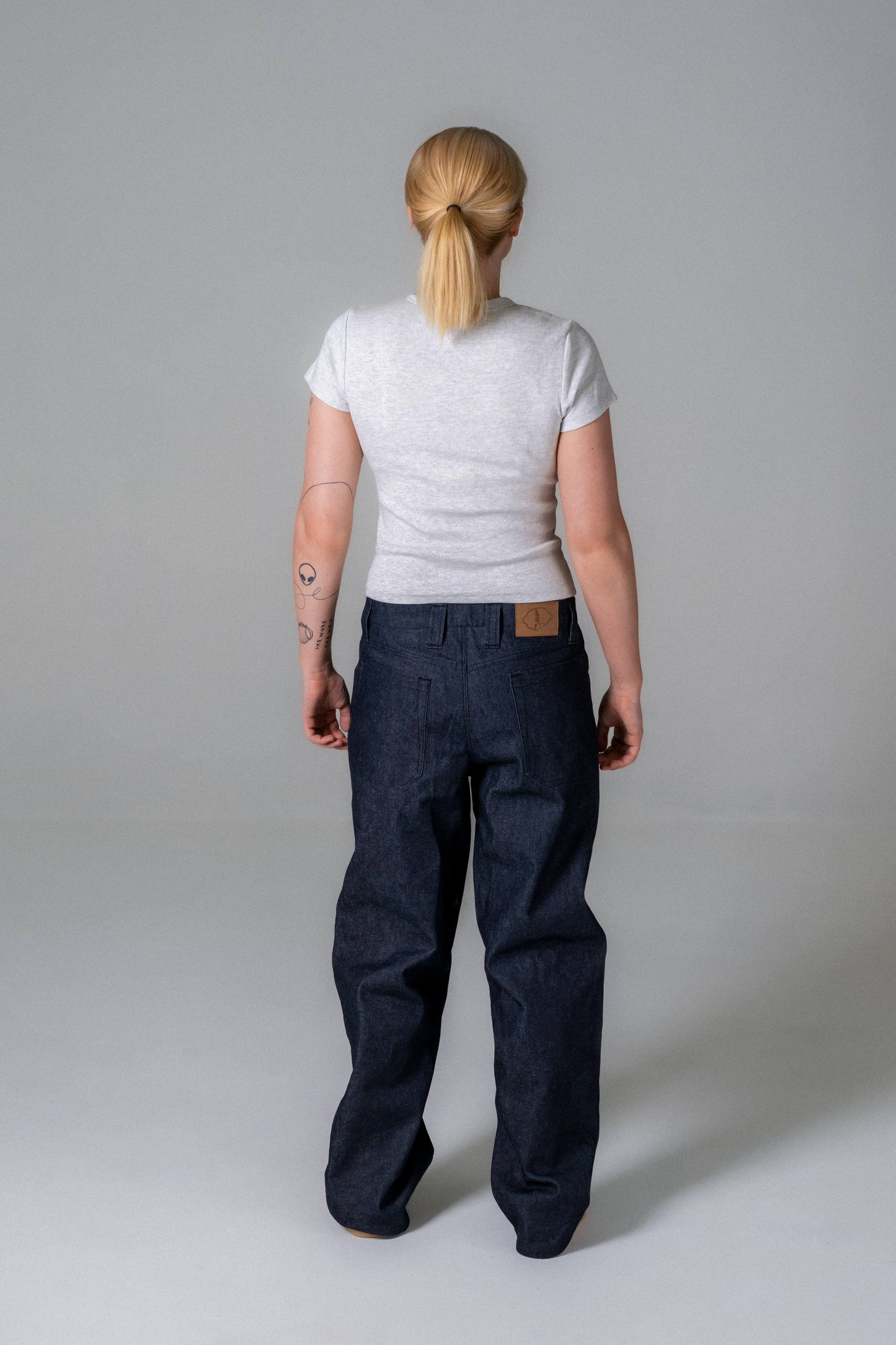 Person wearing a white t-shirt and dark blue jeans on a plain background
