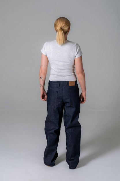 Person wearing a white t-shirt and dark blue jeans on a plain background