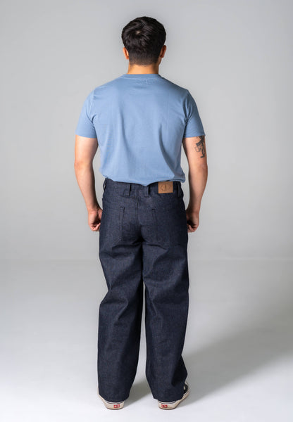 Person wearing a light blue t-shirt and dark pants on a plain background
