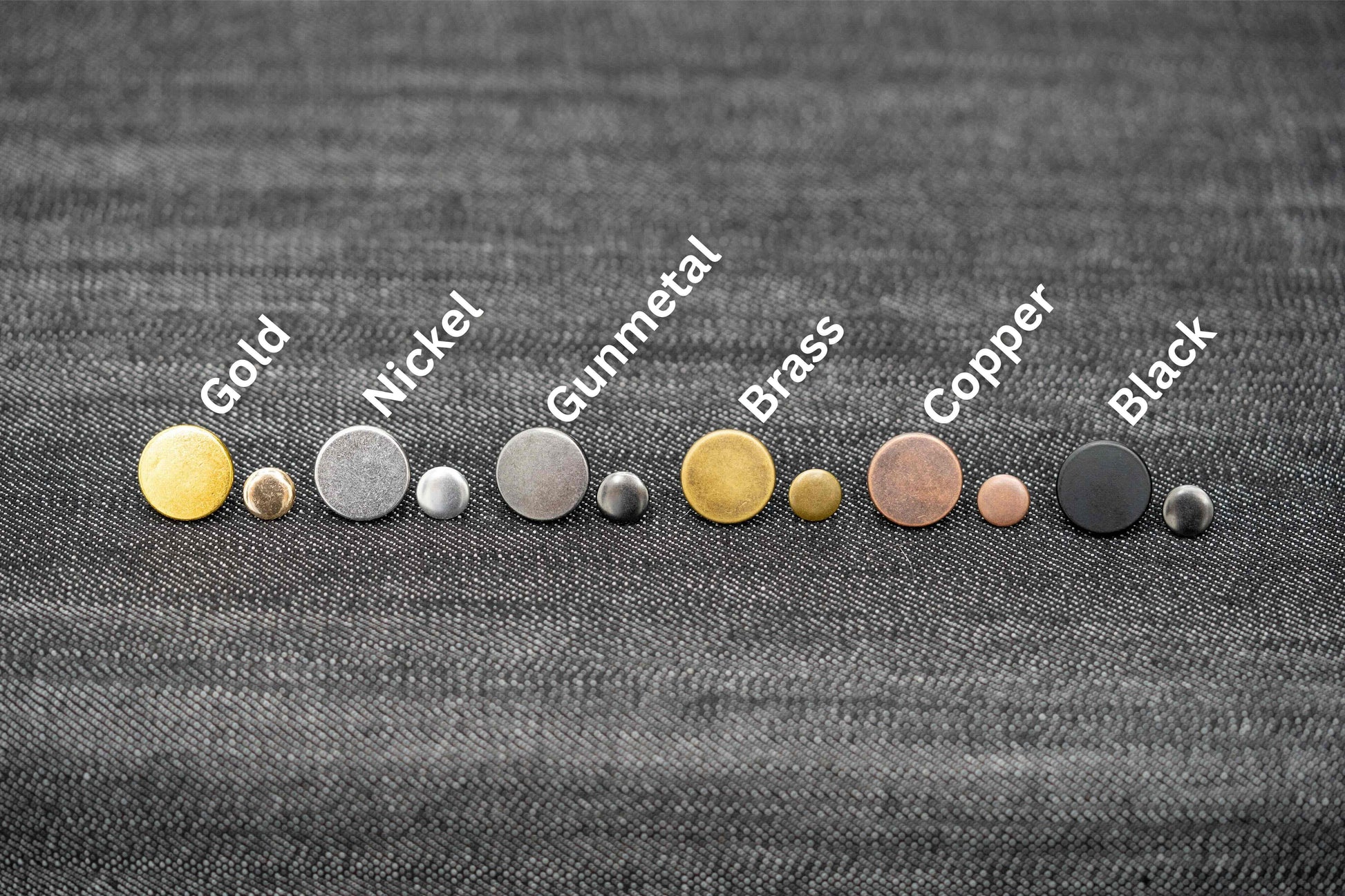 Set of metal buttons in various colors on a textured fabric background