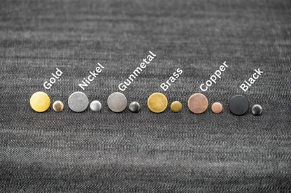 Set of metal buttons in various colors on a textured fabric background
