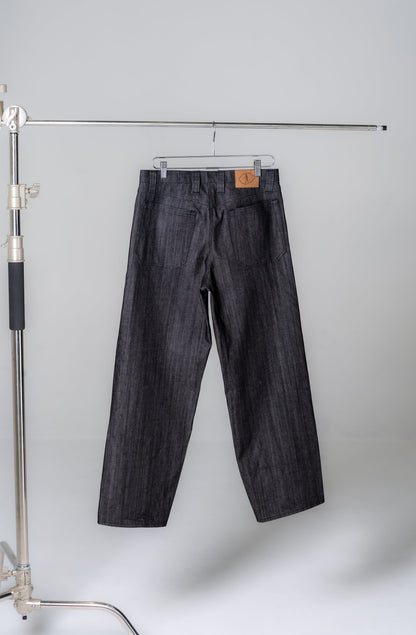 Dark denim jeans hanging on a rack against a plain background