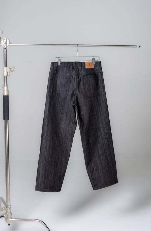Dark denim jeans hanging on a rack against a plain background