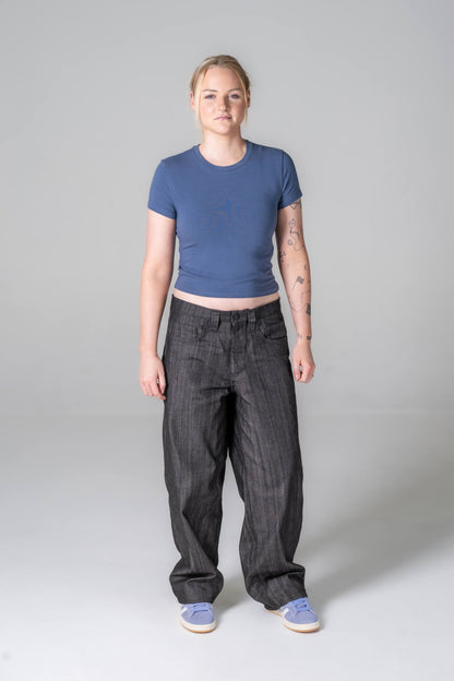 Person wearing a blue crop top and dark pants on a gray background