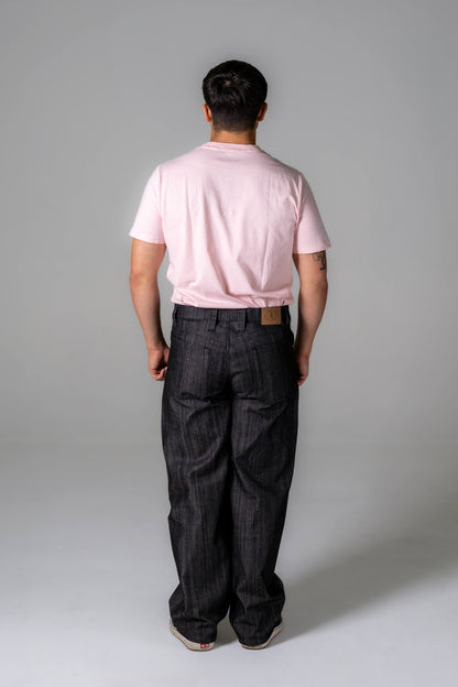 Person wearing a pink polo shirt and dark jeans against a gray background