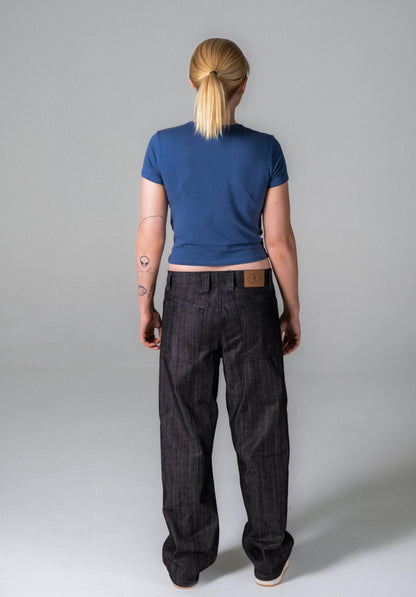 Person wearing a blue top and dark pants on a plain background