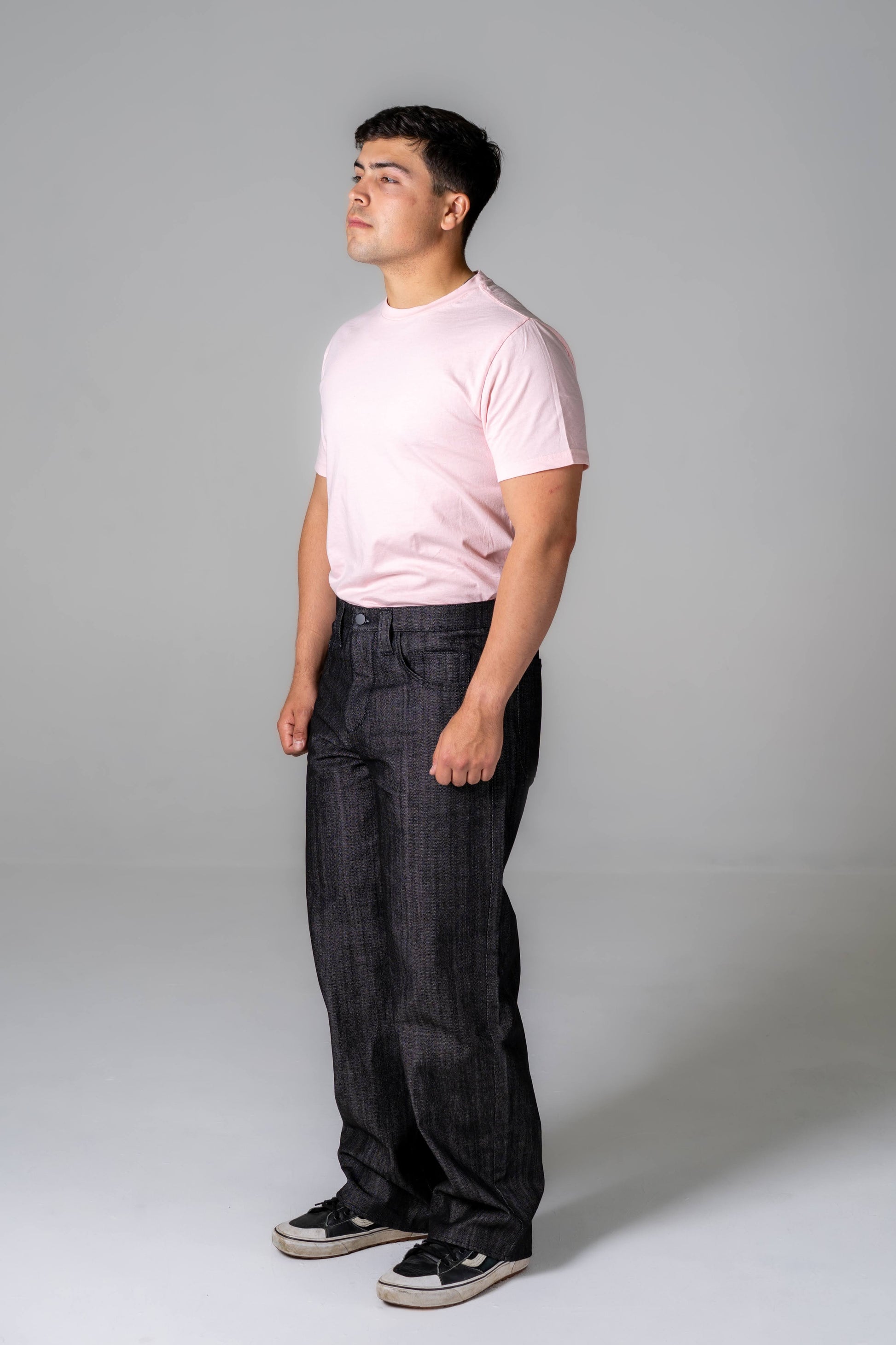 Person wearing a pink t-shirt and black pants against a gray background