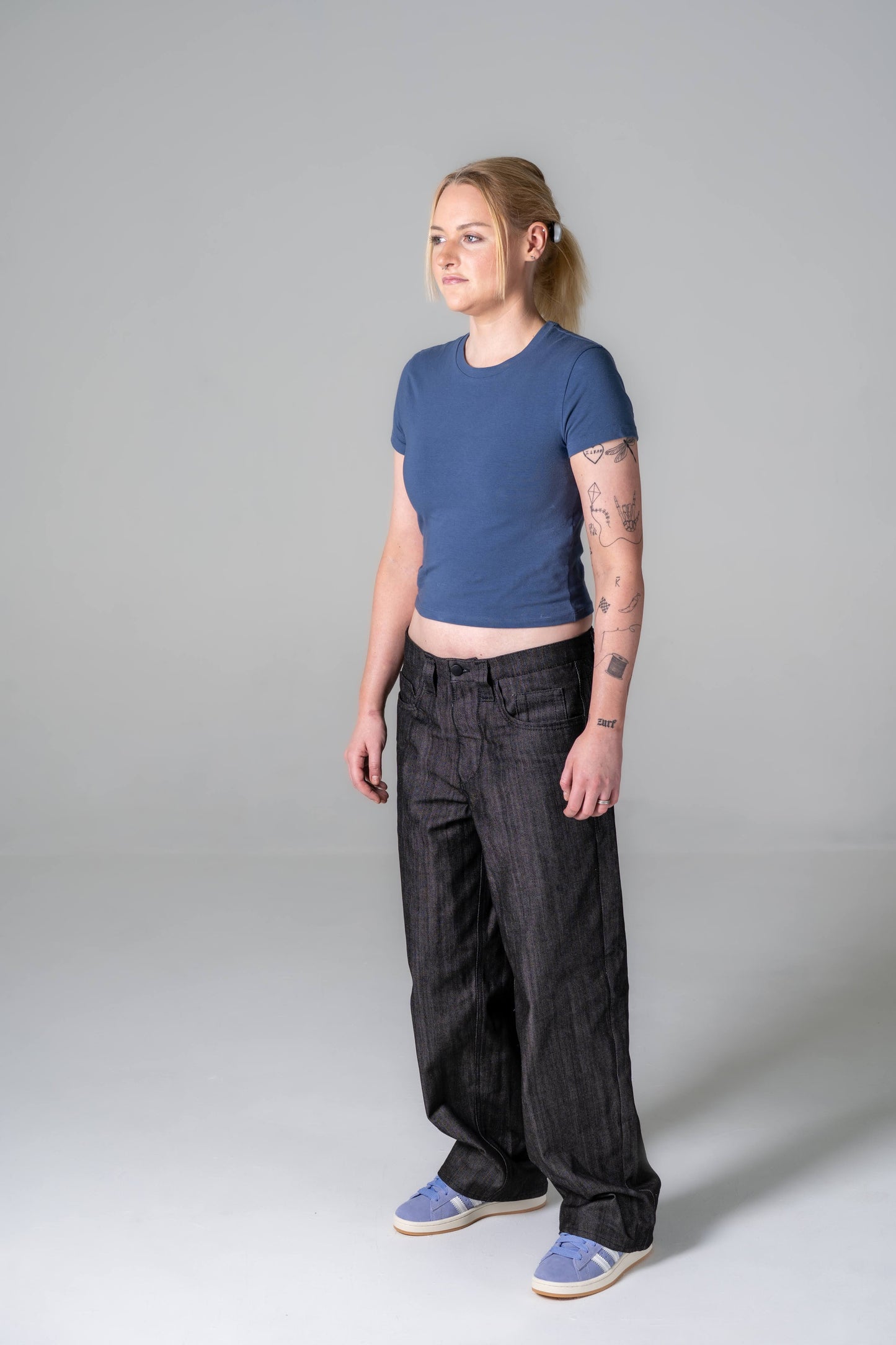 Person wearing a blue t-shirt and black pants on a gray background