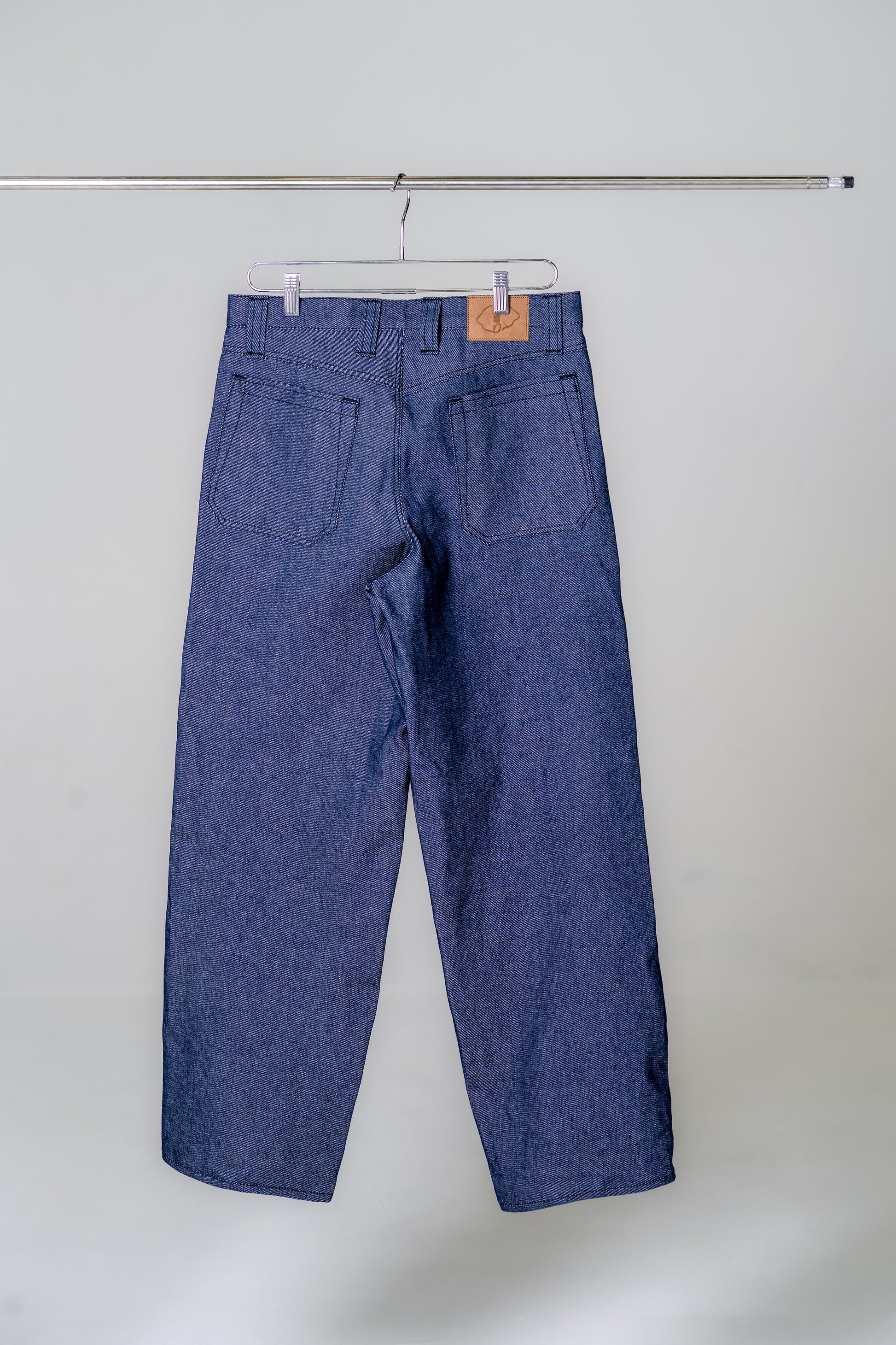 Blue denim pants hanging on a white background