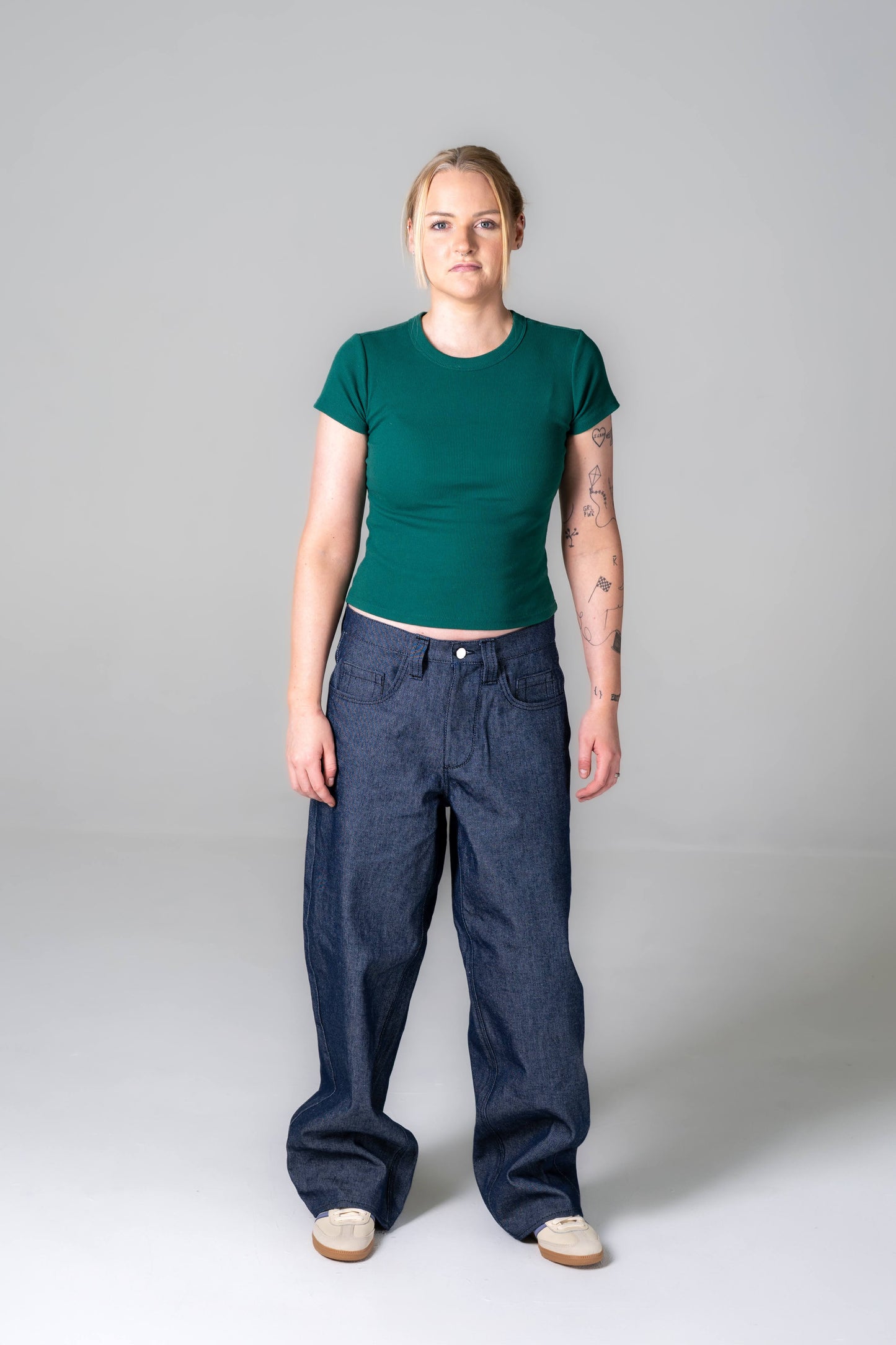Person wearing a green t-shirt and blue jeans on a gray background