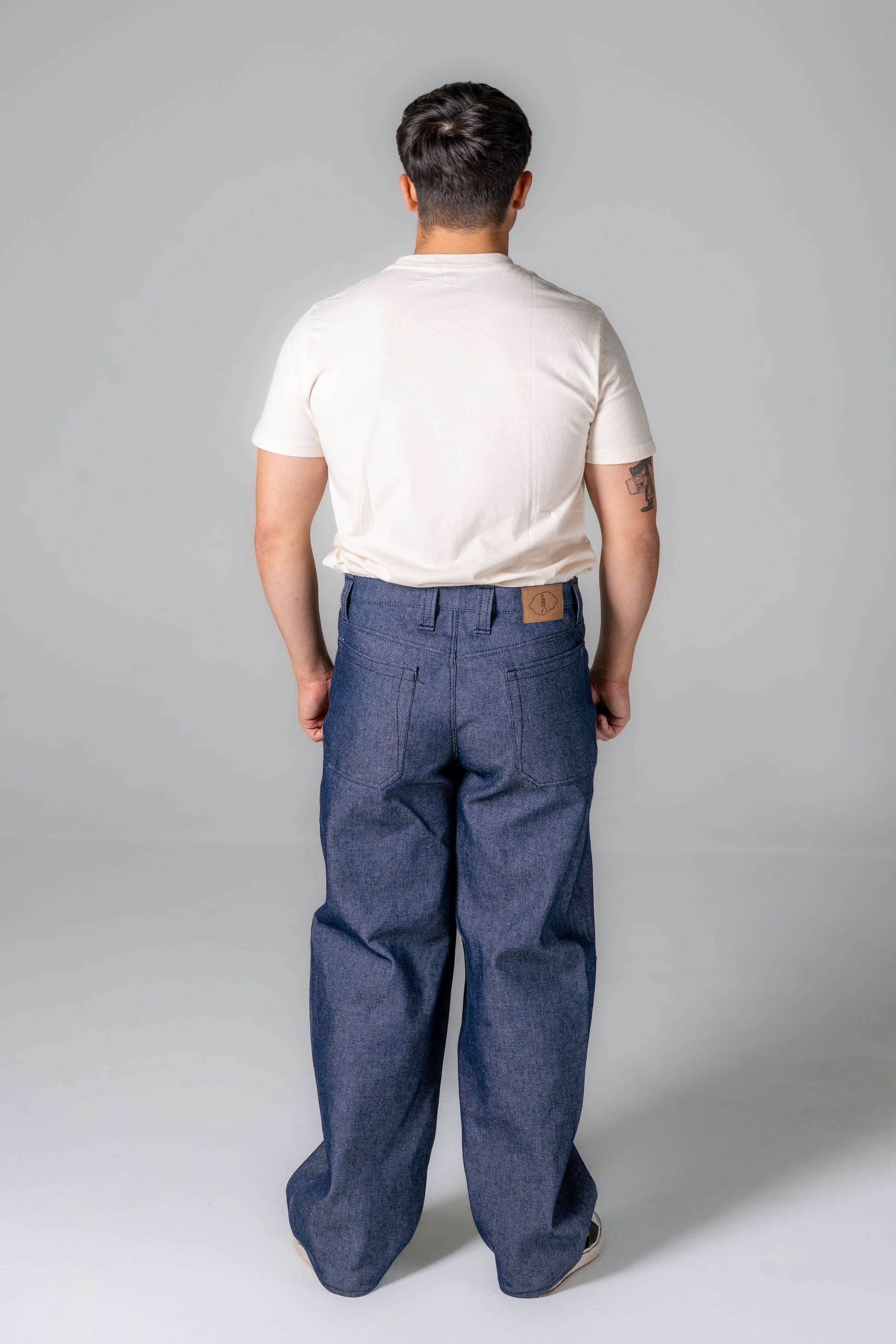 Person wearing blue pants and a white shirt on a gray background