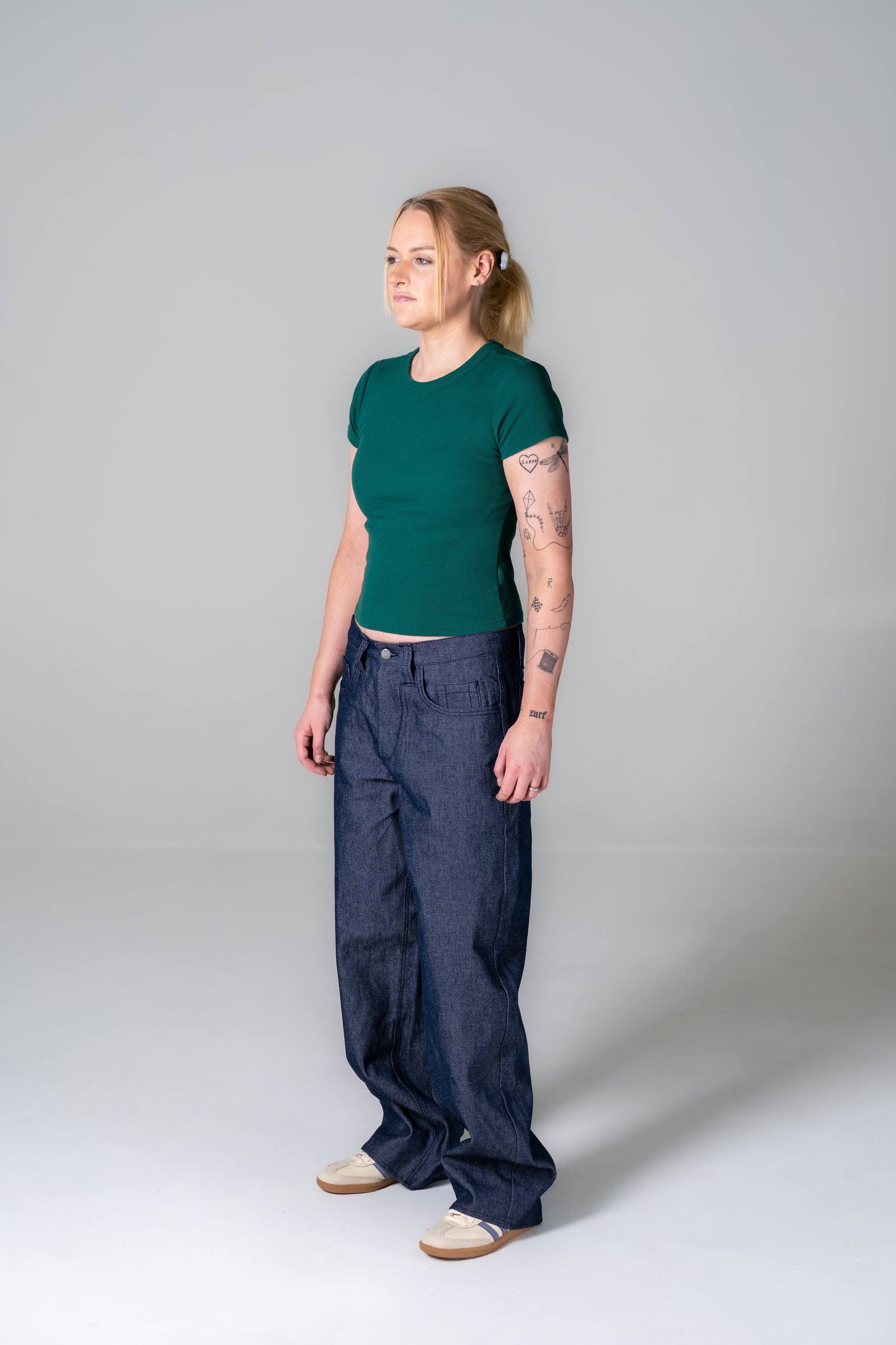 Person wearing a green shirt and blue pants on a plain background